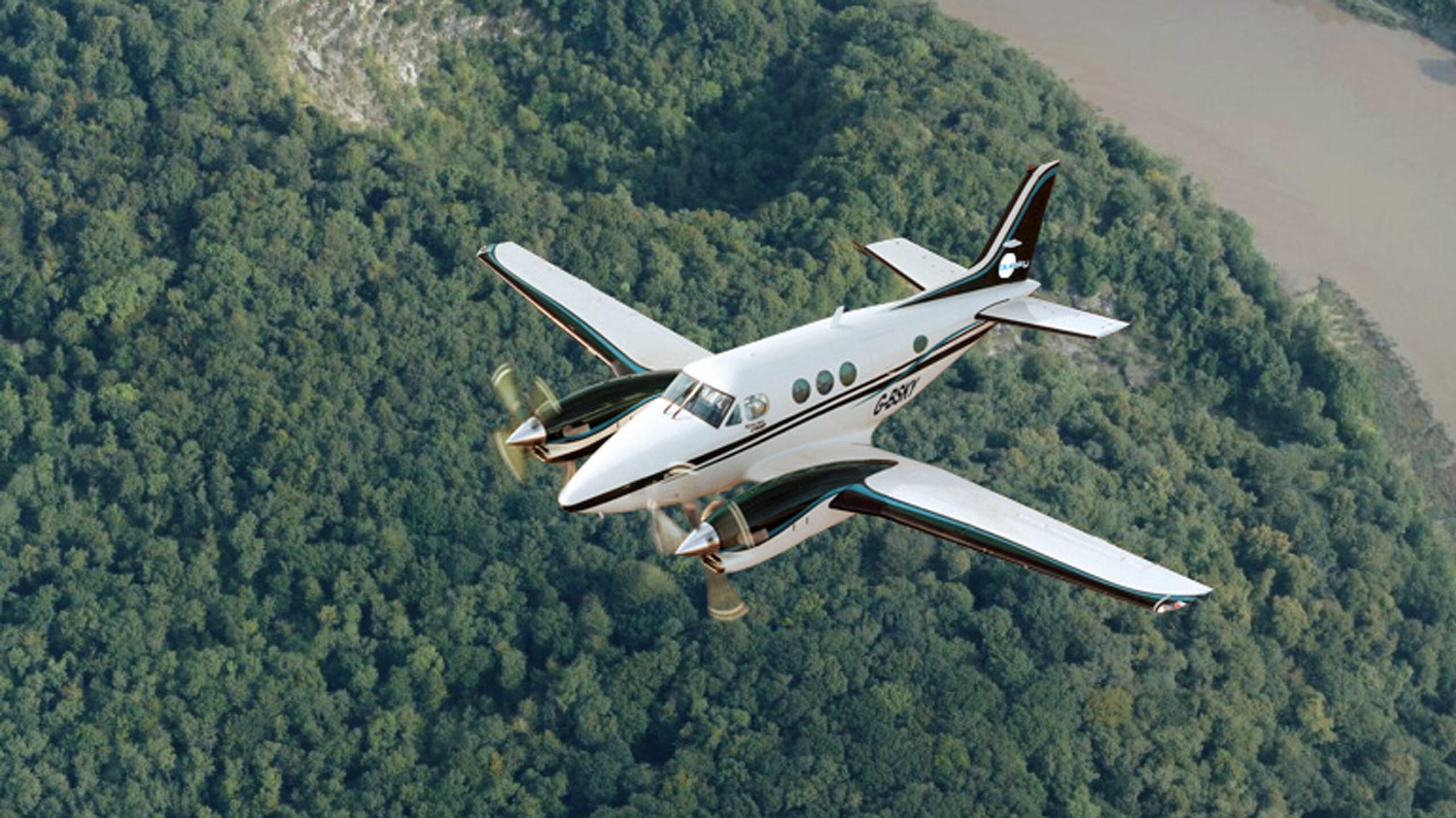 Small plane flying over dense forest in Scotland