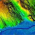 Aerial view of a hillside with height information conveyed by a spectrum of red, green and blue colours.